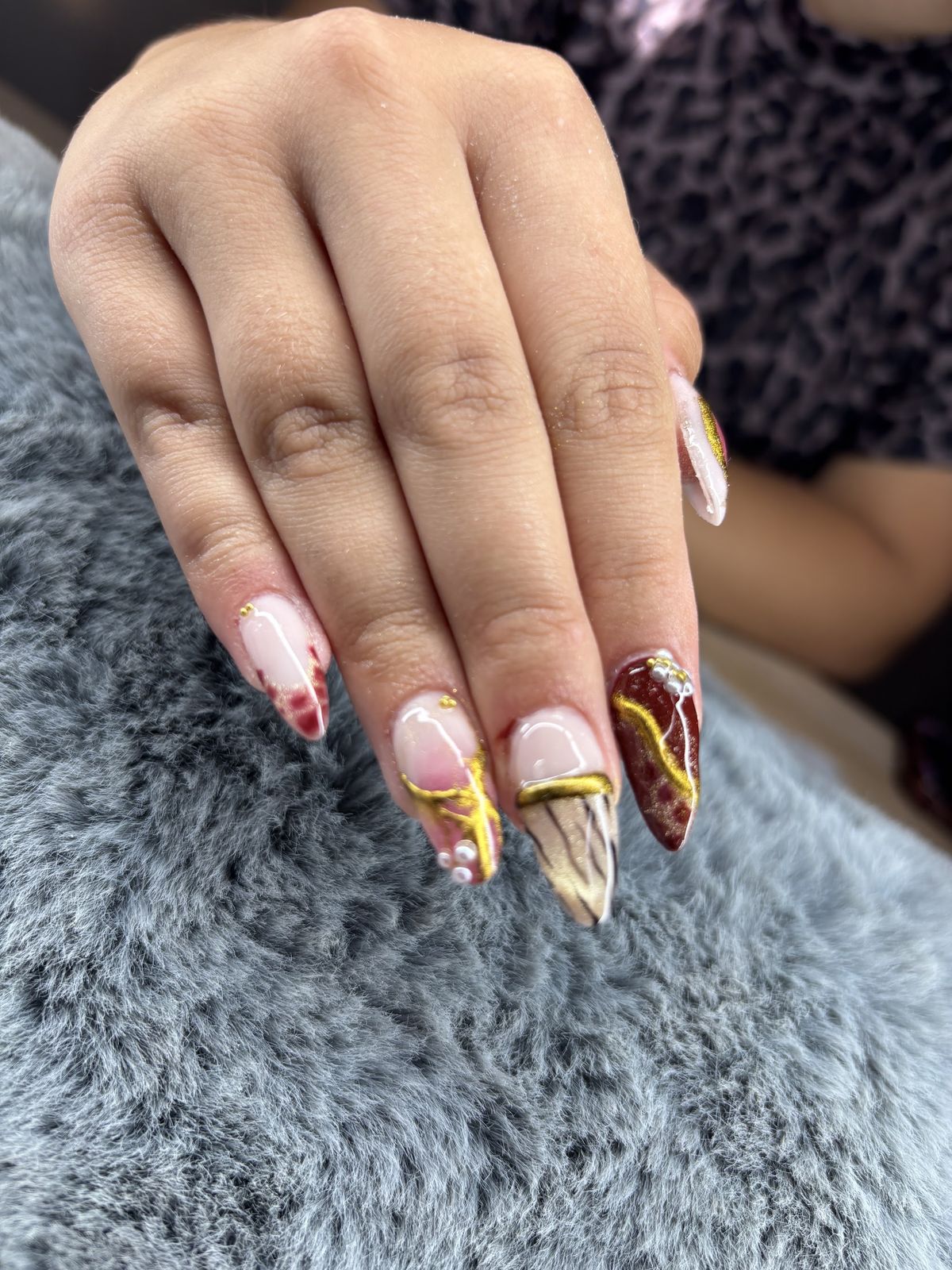 Lange stiletto-nagels in nude, bordeaux en marmer met gouden chrome